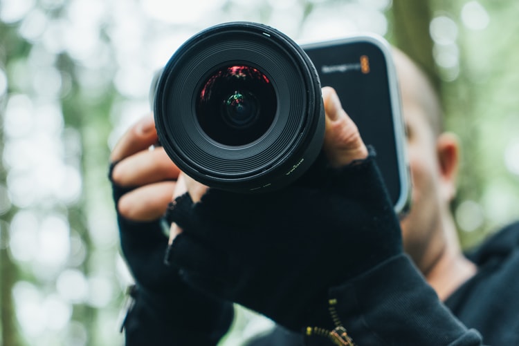 Man in background holding Camera